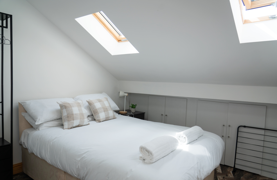 Charming loft bedroom with skylights, slanted ceiling, built-in storage, and cozy under-eaves atmosphere