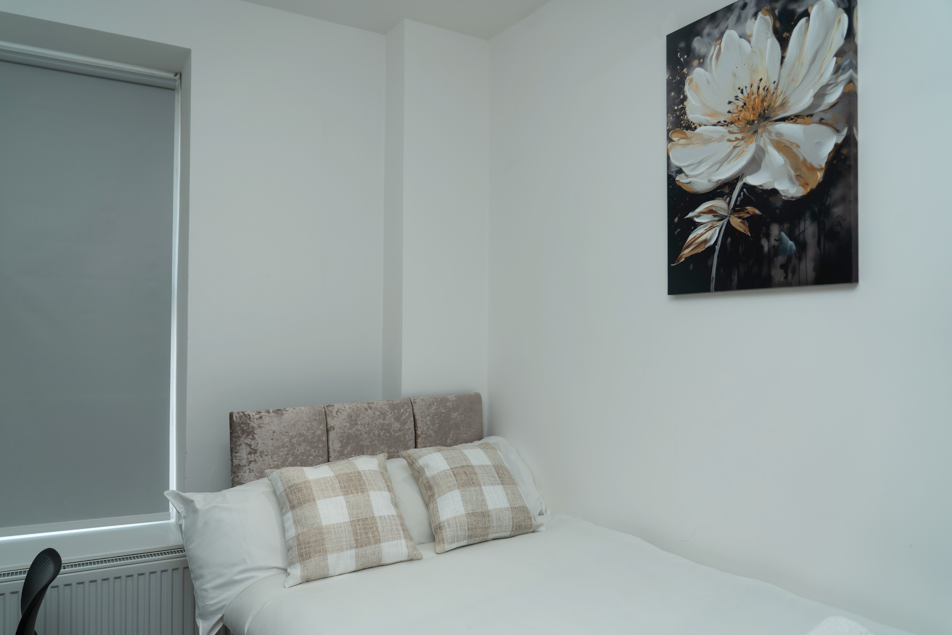 Stylish bedroom with floral artwork, checkered pillows, and modern clean design
